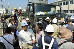 震災で発生したがれきを積んだトラックの前で、集積地への搬入を阻む反対派ら=22日午前9時16分、北九州市小倉北区
