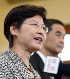 記者会見する林鄭月娥政務官。奥は梁振英行政長官=16日、香港(共同)