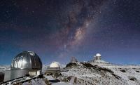 チリのラ・シヤ天文台上空、満天の星空に架かる天の川。欧州宇宙機関(ESA)が5月13日に公開した。アタカマ砂漠の標高約2400メートルの高山には、天体観測の一大拠点がある。左から、ドームに雪が被っているMPG/ESO口径2.2メートル望遠鏡、ESO1メートルシュミット望遠鏡、3.58メートルの新技術望遠鏡(NTT)、ESOの3.6メートル望遠鏡の4基が連なる。<br /><br />Photograph courtesy Jose Francisco Salgado, ESO